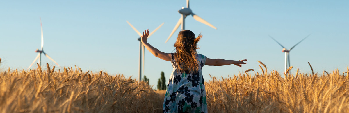 Responsibility - girl running in field with wind turbines in the background